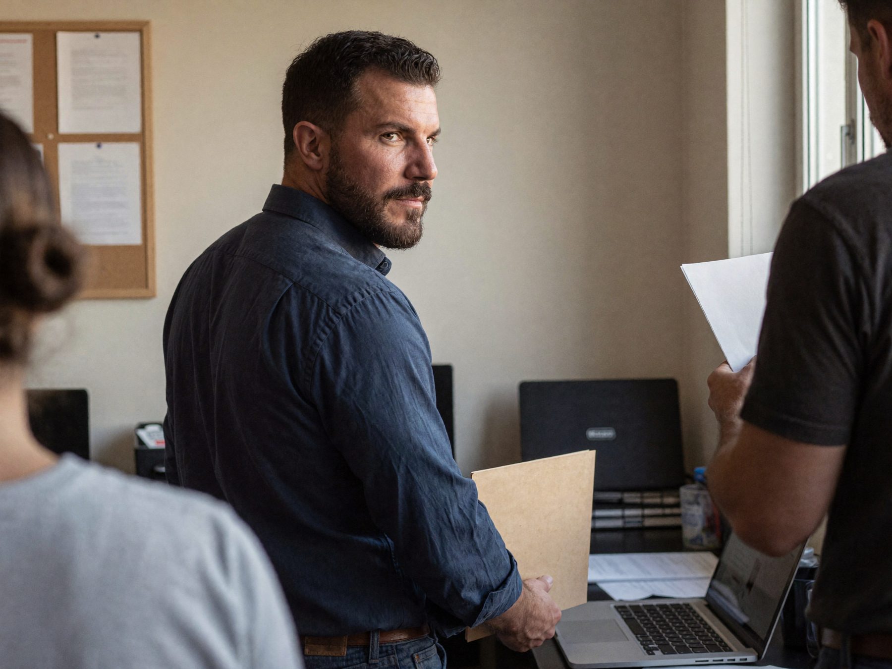 A business owner in a small office handing over a folder