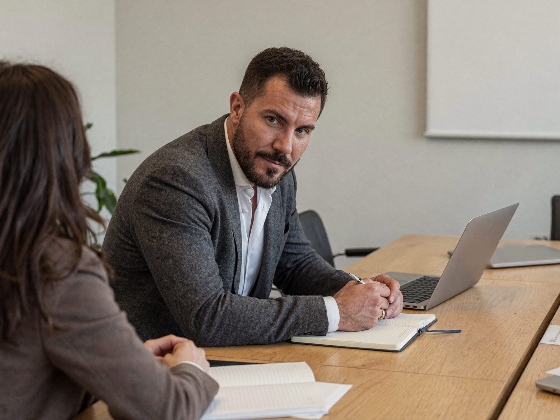A bearded man in a charcoal blazer in a working session with a colleague at a meeting table
